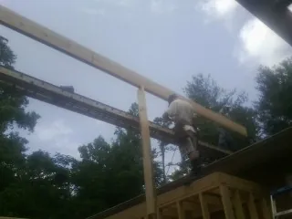 Carpenter setting a ridge beam over a new addition frame — Ice Dam Removal by Roofing Brothers in Walterboro
