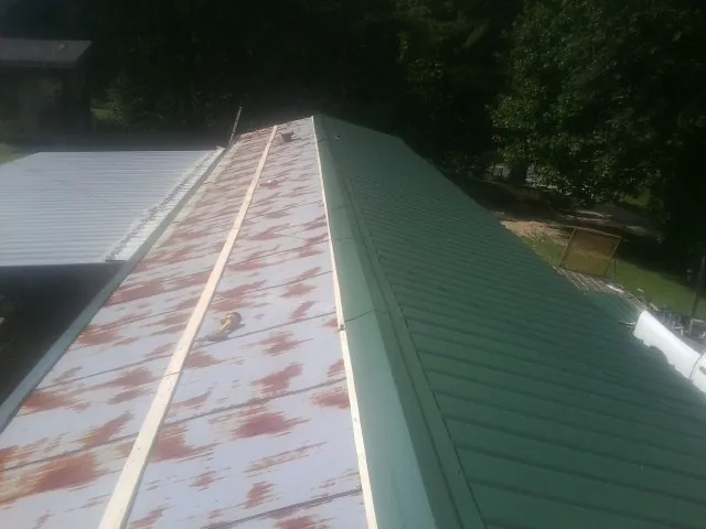 Old rusted panels beside newly installed green metal roofing — Wind Damage Roof Repair by Roofing Brothers in Walterboro