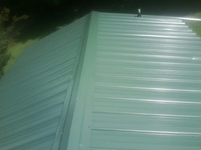New green metal panels meeting at the ridge of a roof — Flat Roof Repair work by our crew in Walterboro