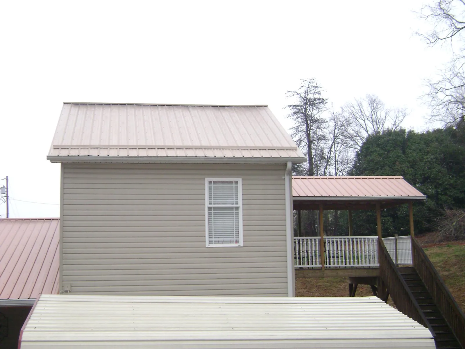 Tan metal roofs on a two story addition and attached porch, from a Roof Replacement job in Walterboro