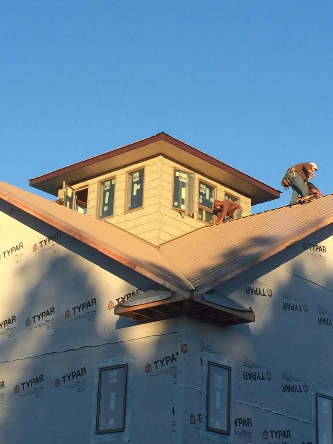 Roofers working around a rooftop cupola on a new metal roof at sunset — Roof Waterproofing in Walterboro by Roofing Brothers